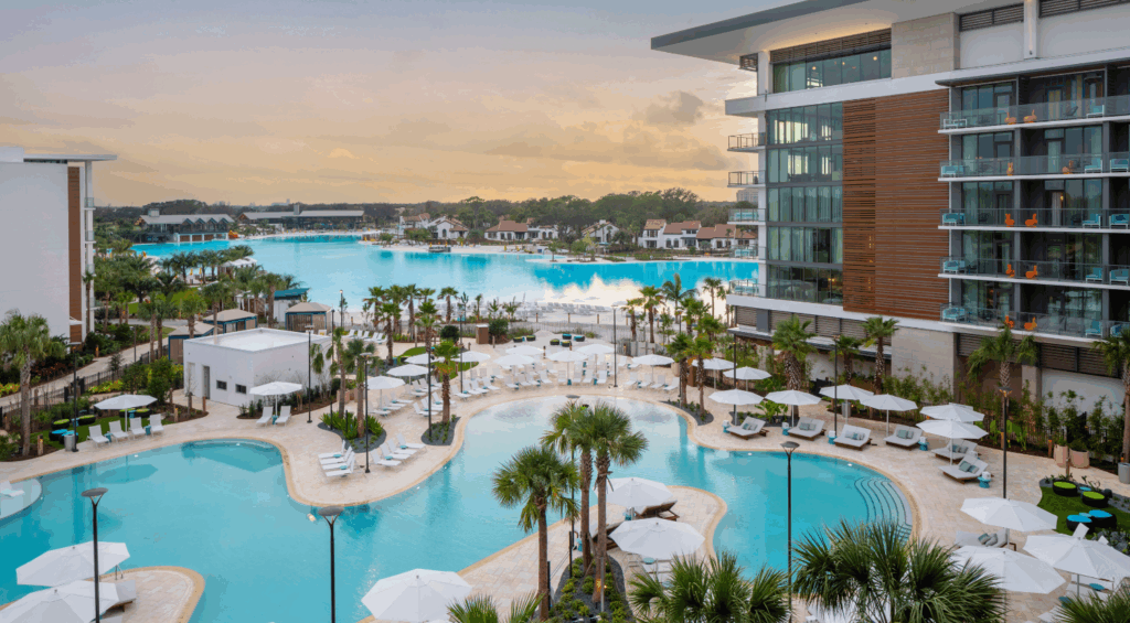 Aerial view of the Conrad Orlando resort with lagoon-style pools and palm-lined deck at sunset.