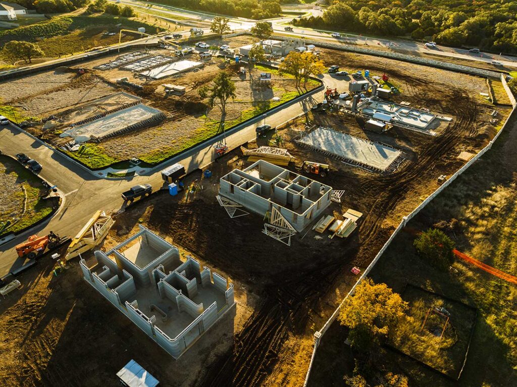 Aerial view of a suburban housing development under construction with multiple home foundations.