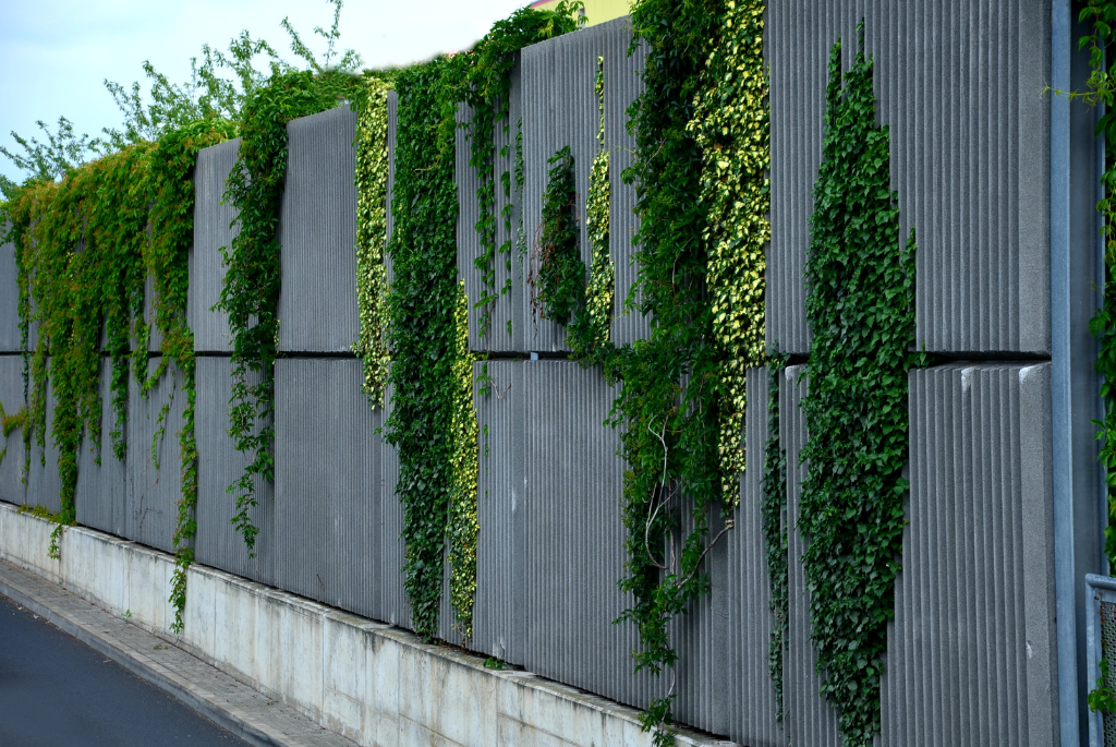 Sound barrier wall with integrated greenery used to reduce traffic noise for homes built near busy roads and highways.