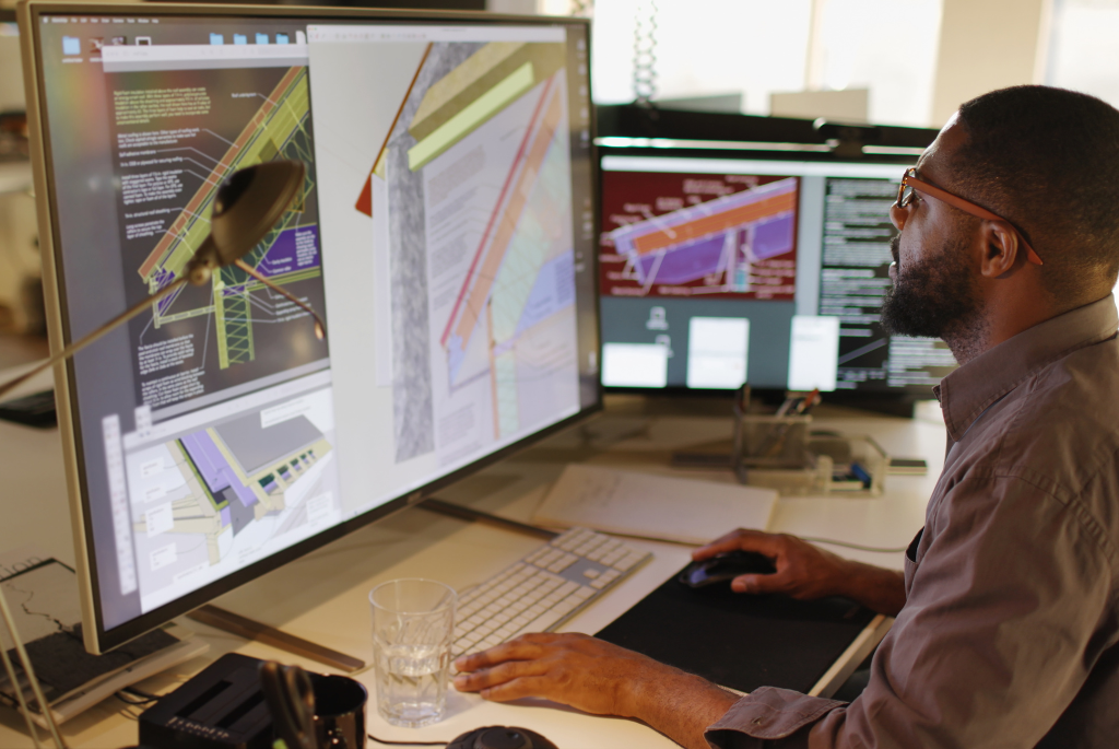 Construction professional reviewing BIM and digital construction plans on multiple monitors
