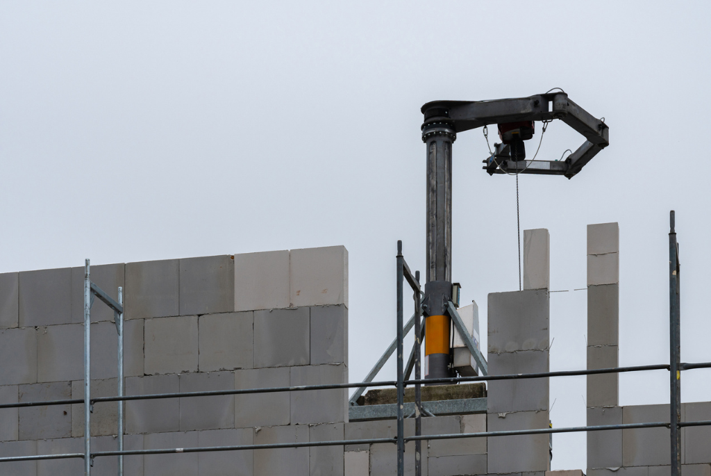 Construction robot installing masonry blocks on a large-scale housing project, automating repetitive work to improve efficiency and safety.