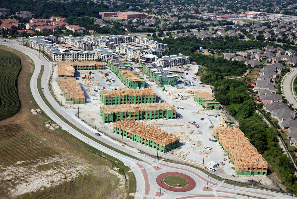 Aerial view of a multifamily housing development under construction in a secondary city, showing large-scale residential growth outside major urban centers.