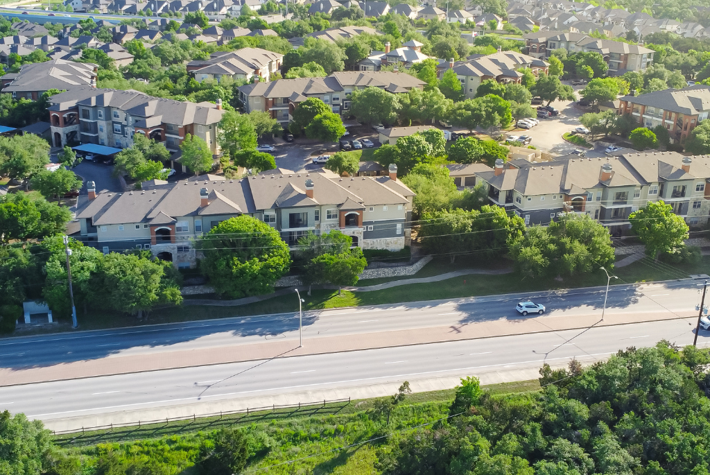 Aerial view of multifamily apartment buildings located near a busy roadway, illustrating design considerations for high-noise environments.