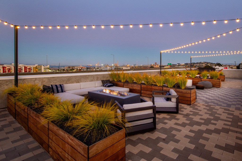 Rooftop amenity space on a multifamily building featuring outdoor seating, fire pit, and landscaped planters.