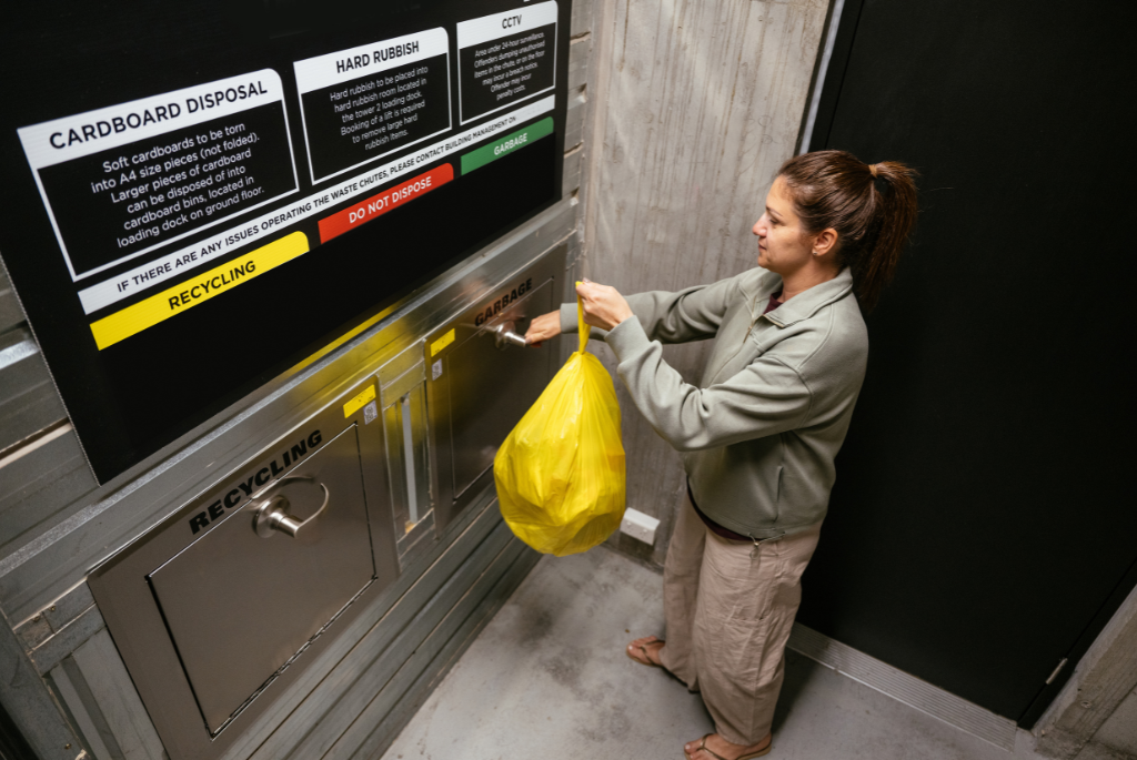 Resident using a trash and recycling disposal system inside a multifamily apartment building.