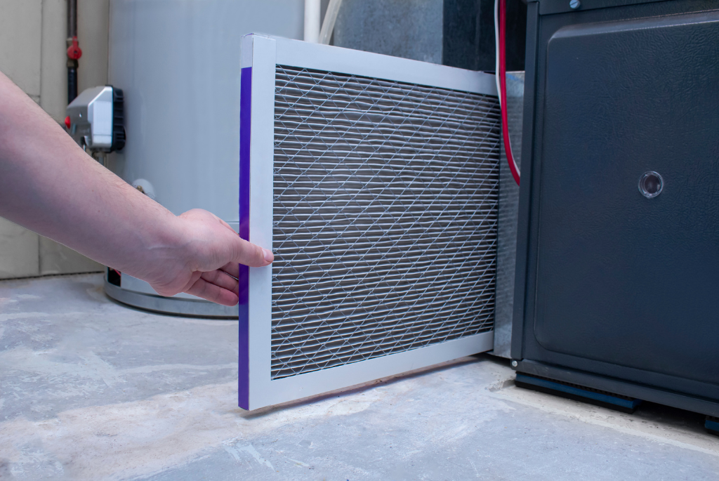 Worker installing an HVAC air filter inside a residential mechanical system.