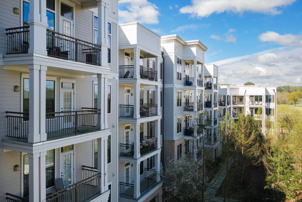 Modern multifamily apartment building with private balconies overlooking landscaped outdoor space.
