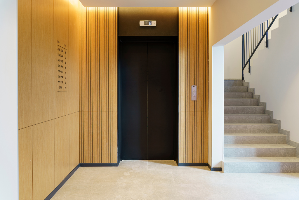 Modern elevator lobby in a mid-rise multifamily building with wood panel walls, stair access and contemporary finishes.