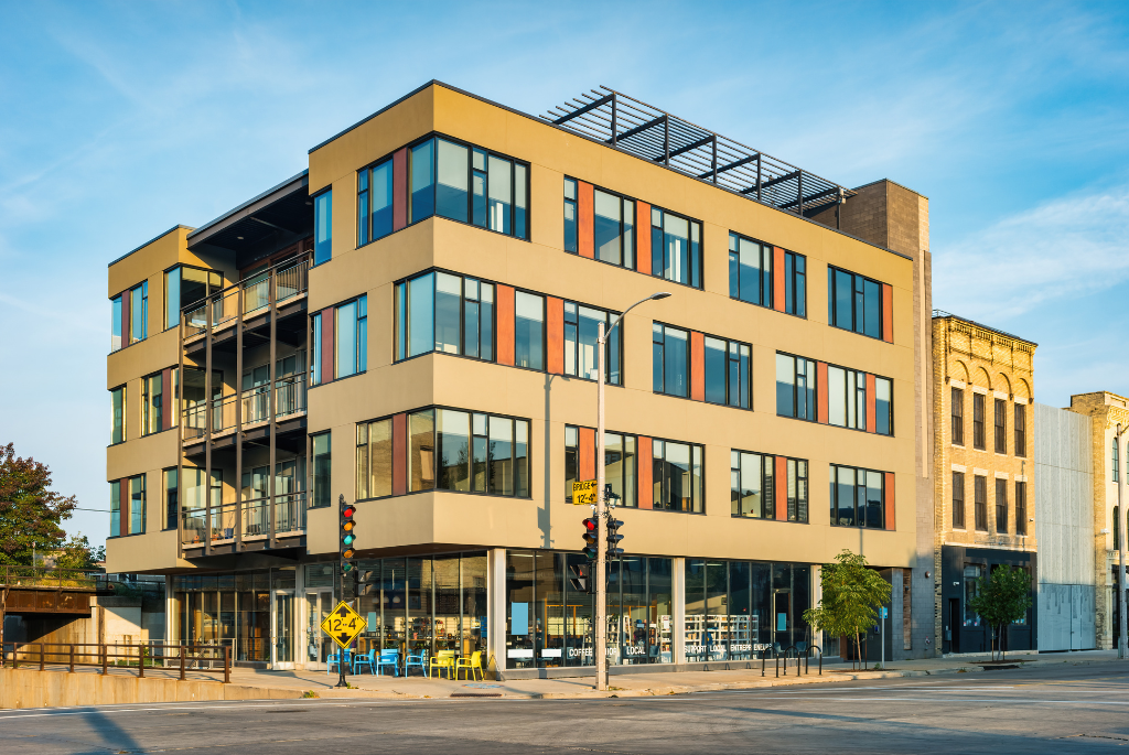 Modern mixed-use apartment building with ground-floor retail space on a city street corner.