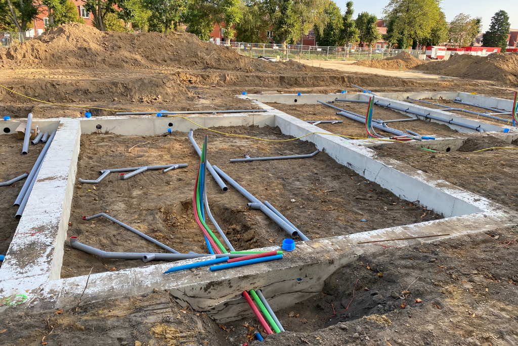 Underground utility lines and concrete foundation work underway at a new residential home development construction site.