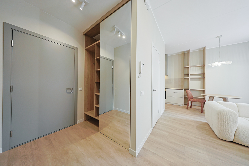Modern apartment interior featuring built-in storage shelving, mirrored closet doors, and an efficient open-concept layout.